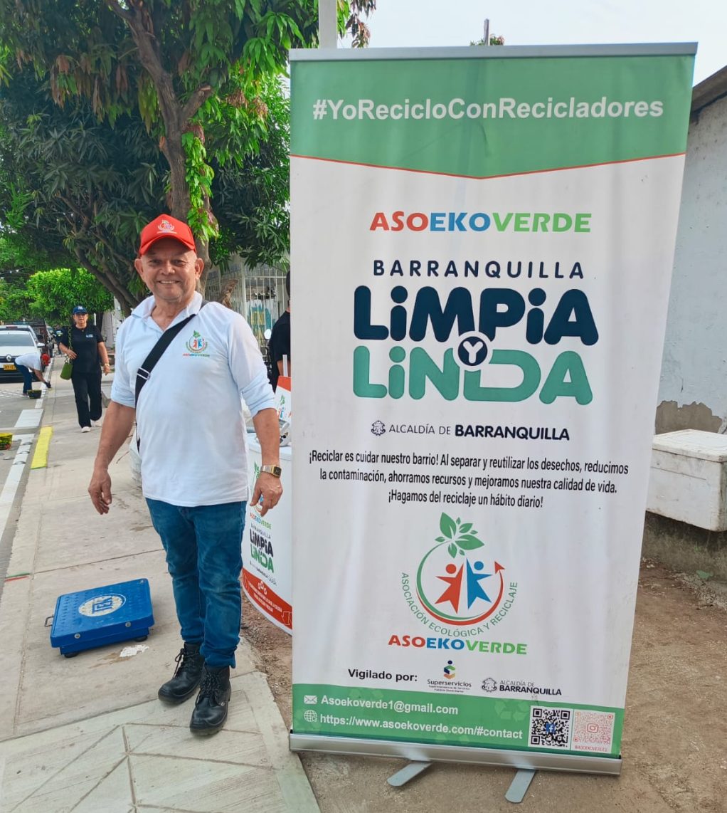 Miembro de ASOEKOVERDE junto al pendón de la campaña Yo reciclo con recicladores, Barranquilla limpia y linda